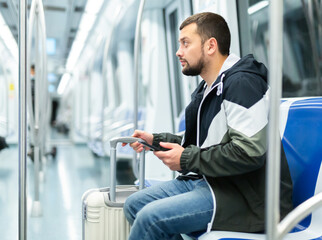 Fototapeta na wymiar Male passenger in casual clothing talking on his mobile phone in subway