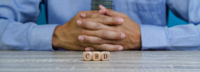 Wide view image of three wooden dices in a row spelling CBD.