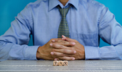 Customer service representative sitting behind wooden dices spelling Tax  on the desk .