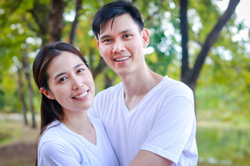Asian couple wearing white shirts Happy smiling in the park. Family concept. health care. outdoor exercise
