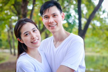 Obraz premium Asian couple wearing white shirts Happy smiling in the park. Family concept. health care. outdoor exercise