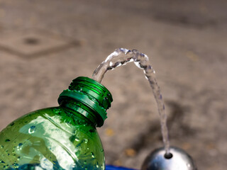 Filling drinking water in an empty plastic bottle. Fresh water from a public water dispenser in an...