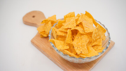 Selicious nachos chips in glass bowl on a cutting board, isolated on white background