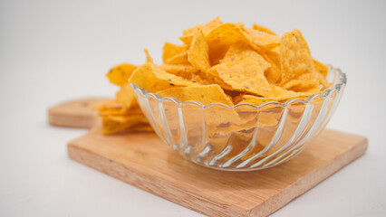 Selicious nachos chips in glass bowl on a cutting board, isolated on white background
