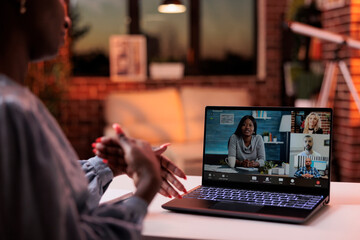 Businesswoman chatting with coworkers online using videocall software and laptop, back view....