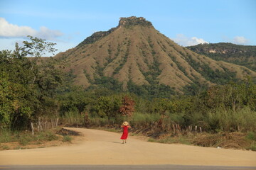 Mulher de vesrido vermelho caminhando em frente ao morro do Segredo, Lajeado, Tocantins
