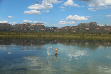 Mulher jogando agua para cima com Montanhas refletidas na água em Lagoa da serra, Rio da Conceição, Tocantins
