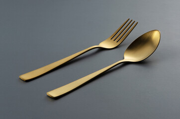 Gold knives and spoons set against a black background.
