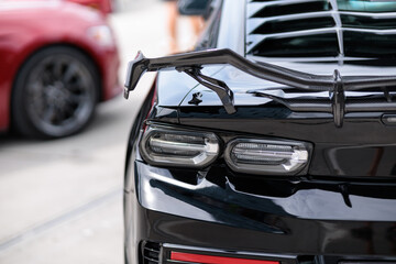 Luxury black sports car fragment, rear aerodynamics carbon spoiler and rear lights - obrazy, fototapety, plakaty