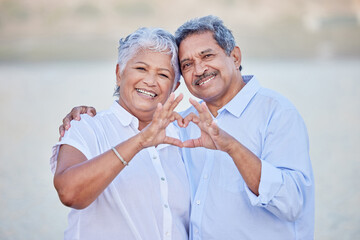 A happy senior couple with a heart sign with their fingers and enjoying fresh nature air on...
