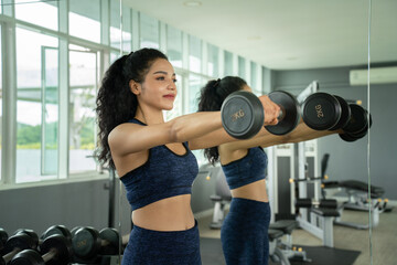 Beautiful young Girl weight training with dumbbells at Gym. Sport, healthy lifestyle. Athletic...
