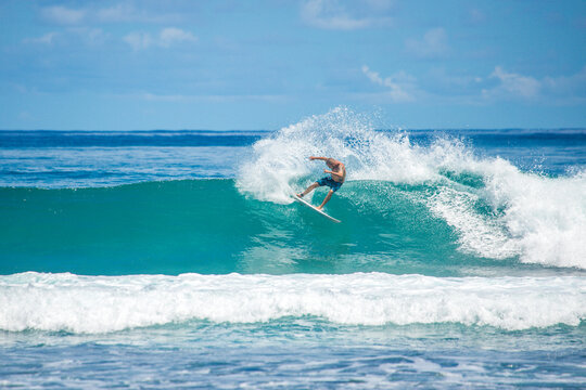 Surfer riding blue wave at Mentawai islands, Sumatra, Indonesia