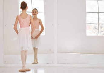 Young ballet dancer dancing in studio, doing dance performance before competition and learning creative sport in mirror at school. Girl ballerina training her balance and child in start position © Alex S/peopleimages.com