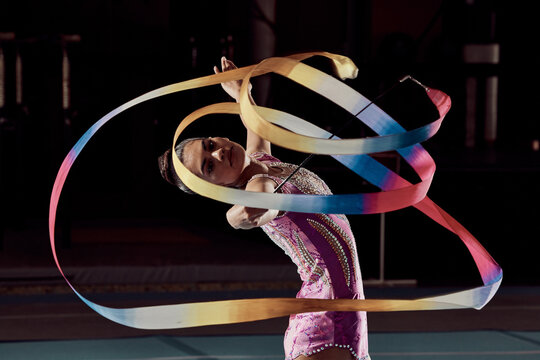 Woman dancing with ribbon in concert in arena, dancer doing creative, artistic and cardio dance and training a performance in dark studio. Girl gymnast doing sport workout and strong in competition
