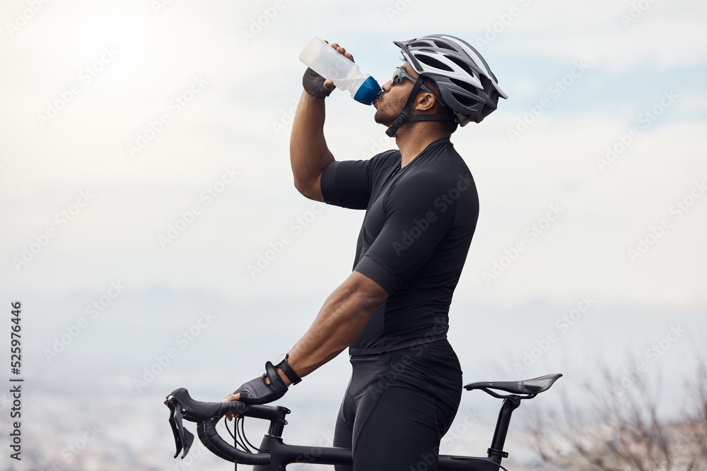 Wall mural Sports man with a bike drinking water bottle doing fitness training or workout on sky mockup background. Healthy, professional athlete cyclist with a bicycle during cycling cardio exercise in nature