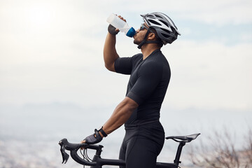 Fototapeta Sports man with a bike drinking water bottle doing fitness training or workout on sky mockup background. Healthy, professional athlete cyclist with a bicycle during cycling cardio exercise in nature obraz