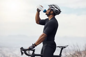 Rolgordijnen Sports man with a bike drinking water bottle doing fitness training or workout on sky mockup background. Healthy, professional athlete cyclist with a bicycle during cycling cardio exercise in nature © Clement Coetzee/peopleimages.com