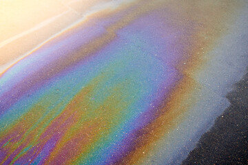 Obraz premium Oil stain on the asphalt, rainbow-shaped colored gasoline stains on an asphalt road as a texture or background