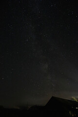 Starry sky with milky way above silhouette of old house in village