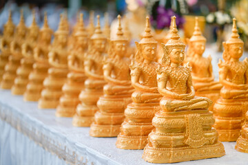 Golden Buddha statues placed on the white table, which were wet by rain felled and prepared for a religion ceremony event.