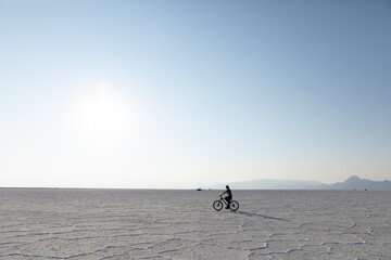 Fototapeta na wymiar Young woman riding a bike on Bonneville Salt Flats in Utah