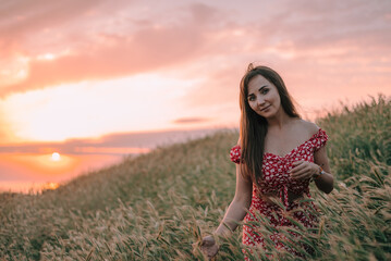 young woman touching spikes of tall grass in the mountains at sunset