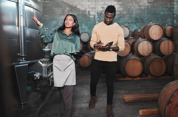 Man, woman and winemaker giving tour to new employee learning logistics in a winery or wood barrel...