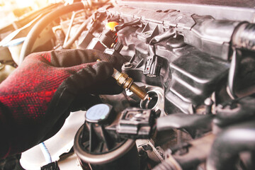 A auto mechanic is installing automobile iridium spark plugs into the ignition socket of the engine...