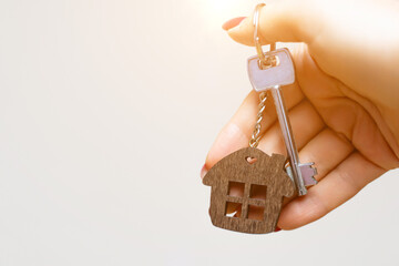 A woman's hand holds a house key on a white background with copy space. Real estate agent. Buying a...