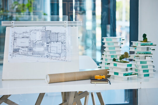 Architecture, blueprints and model building design in empty architectural company office. Vision engineering, real estate or residential planning with 3D structure for luxury apartment infrastructure