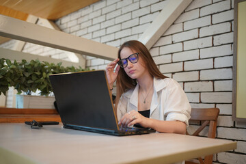 Technology and people concept, young woman using laptop and internet technology and sitting on the desk with laptop computer.