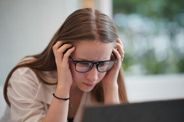Indoor shot of young woman looking at laptop seriously. Female sitting at home office and working...