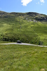 Schwarzer Geländewagen mit Dachzelt steht auf einrr Single Track Road im Tal Glen Etive in den...