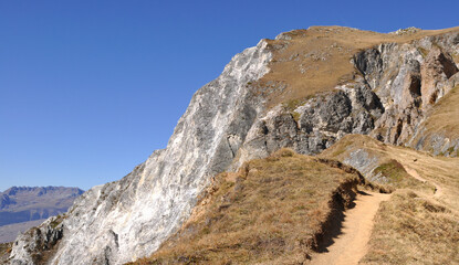 hiking trail in high altitude in the Alps rocky  mountains under clear blue sky