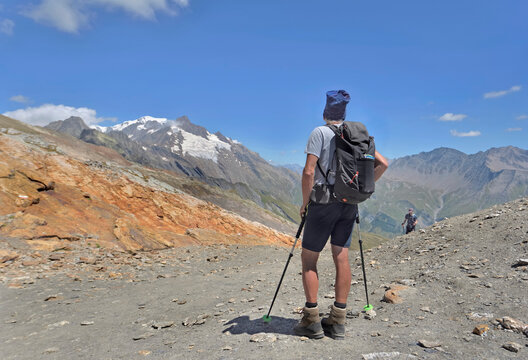 a hiker standing on the trail of the tour of Mont Blanc in summer znd looking the glaciers far away