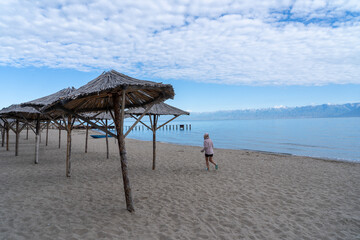 The girl runs along the beach against the backdrop of the lake and mountains