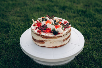 Cake for a child with a candle in the form of the number one, for the first birthday, on a green lawn, at sunset with a blurred background