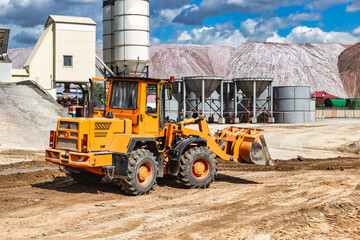 Fototapeta na wymiar A large front loader transports materials in a concrete production plant. Production of concrete. Transportation of bulk materials. Construction equipment. Bulk cargo transportation.