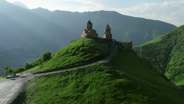 Gergeti Trinity Church On The Hilltop Of Green Mountains In Kazbegi, Georgia. - aerial