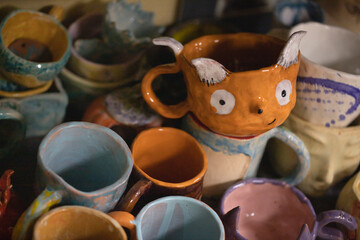 Handmade ceramic mugs in the form of a fox and other various shapes and colors. Clay mugs painted in various colors.