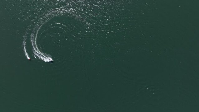 Aerial view of a boat pulling a tube at high speed on a Dutch lake
