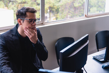 Man with computer with doubt face. Blond Caucasian man who works in an office with a window behind...