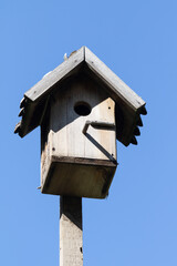 Old wooden birdhouse against the sky of a residential building