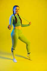 Fototapeta na wymiar girl in a sports top and leggings. athlete in golf. Sports girl doing exercises for the buttocks with a resistance band on a yellow background. Fitness woman exercising. yellow background