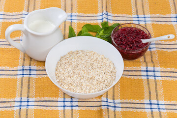 Raw rolled oats, hot milk and red currants on table