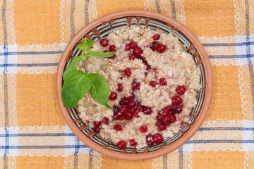 Oats porridge with fresh red currants in bowl, top view