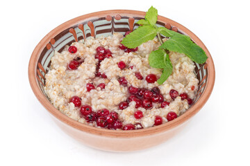 Oats porridge with red currants in bowl on white background