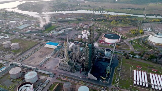 Aerial orbit of an oil refinery and its fractionation tower with the tanks in the background, natural environment.
