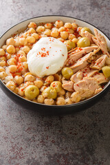 Tunisian dish Lablabi or Lablebi based on chick peas in a thin garlic and cumin broth topped with a poached egg and tuna closeup in the bowl on the table. Vertical