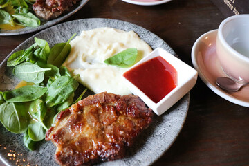 pork steak with sauce and herbs on a plate on a wooden table